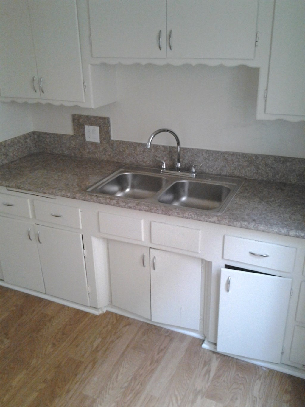 an empty kitchen with white cabinets and a sink