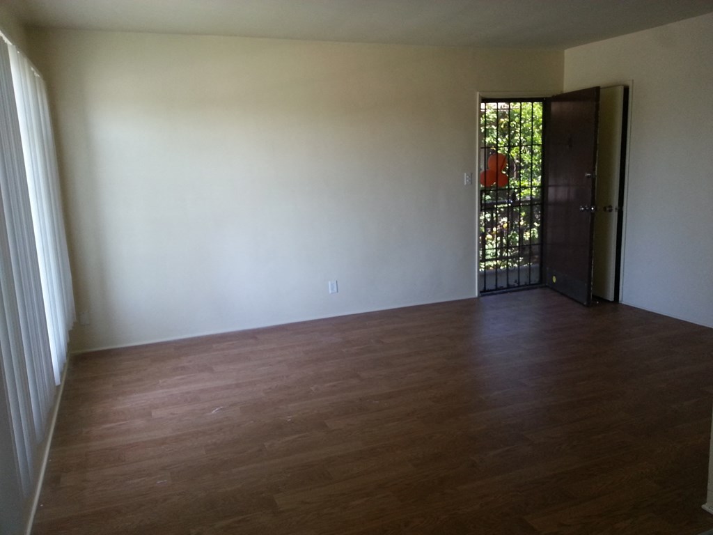 an empty living room with white walls and wood floors