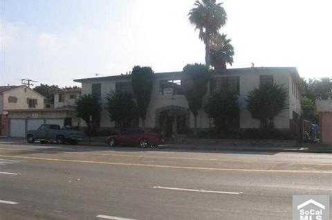 a building with palm trees and cars parked in front of it