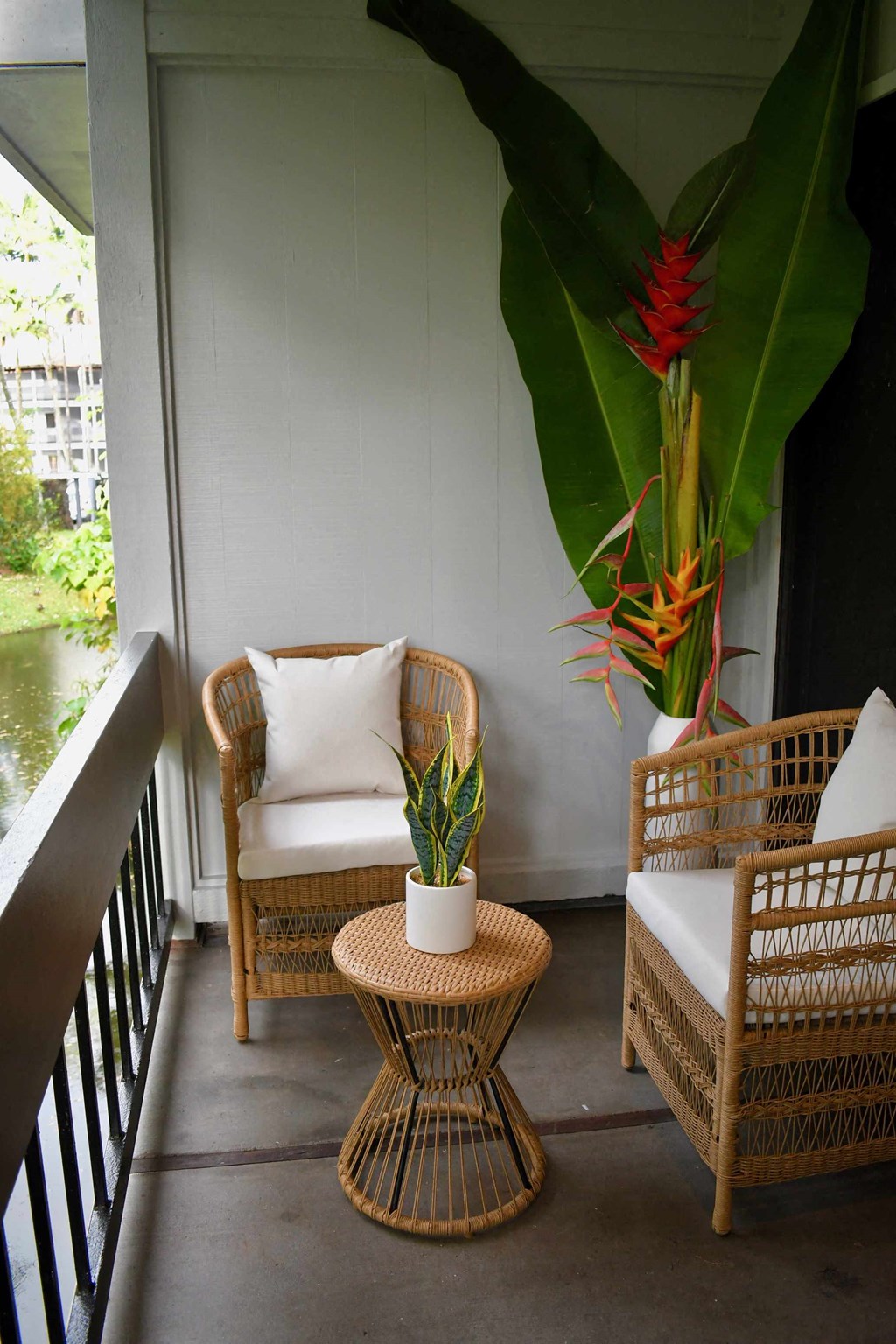 a porch with two chairs and a table with a plant