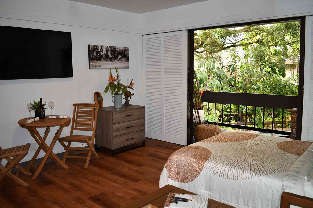 a bedroom with a bed and a desk and a balcony