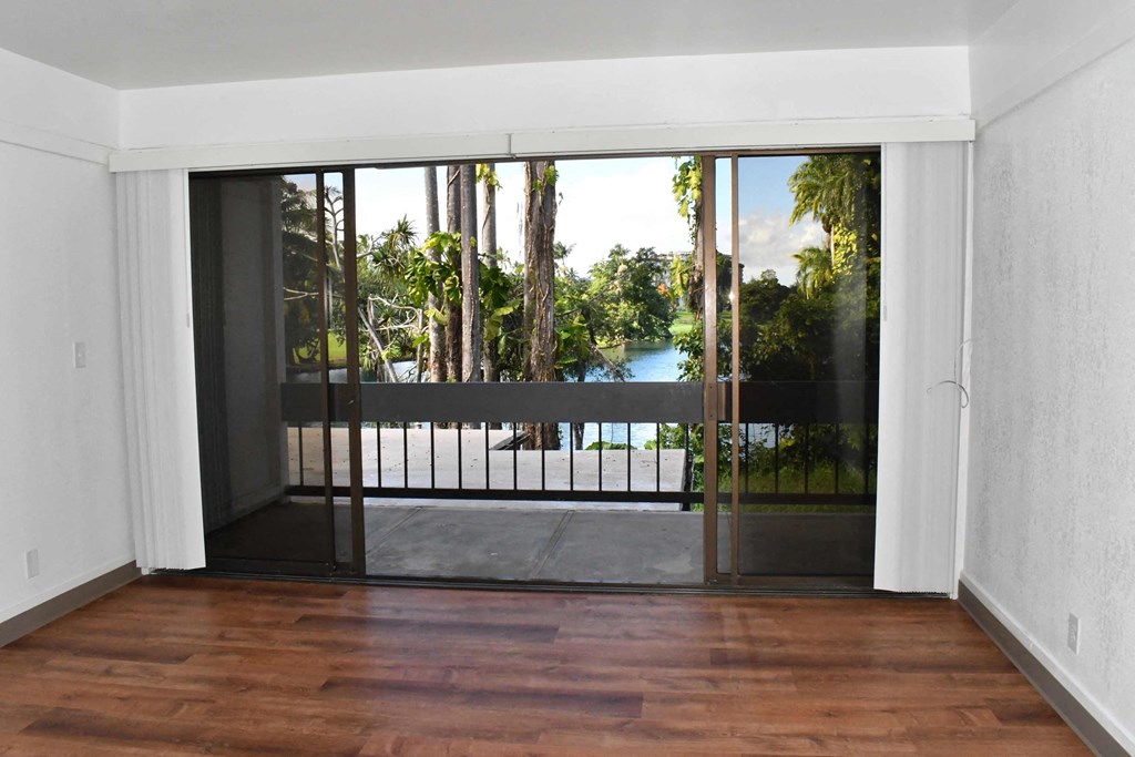 an empty living room with a balcony and a view of a lake