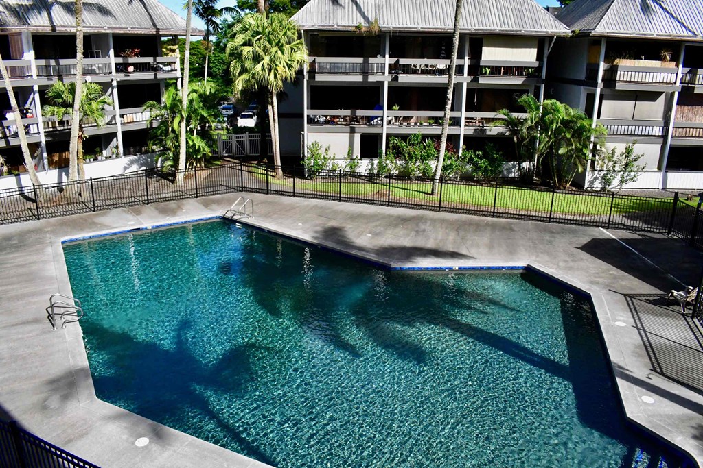an empty resort pool with an apartment building in the background