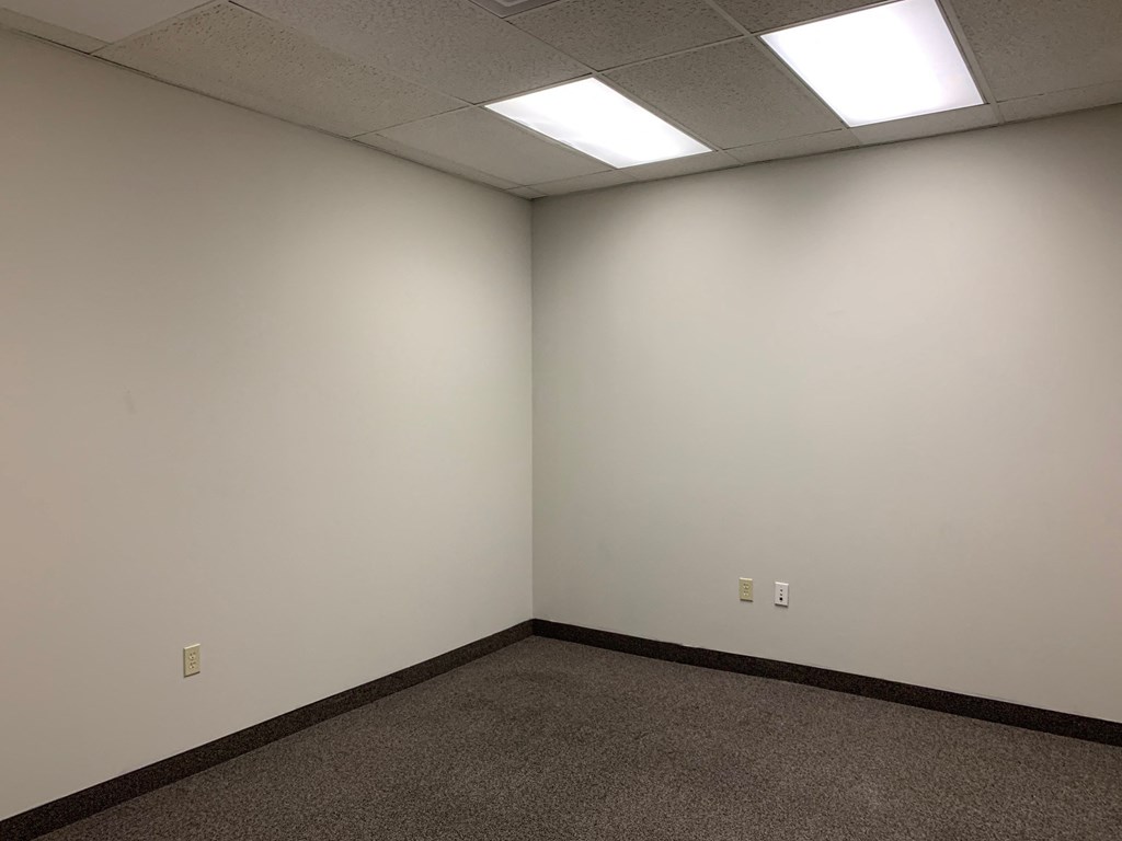 an empty room with white walls and a ceiling light