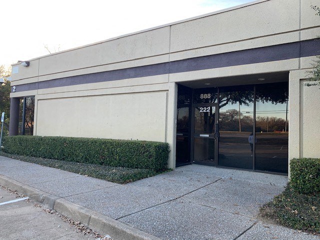 a white building with a door and a sidewalk