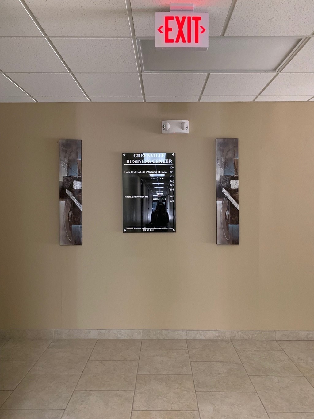 a wall with three pictures on it and an exit sign