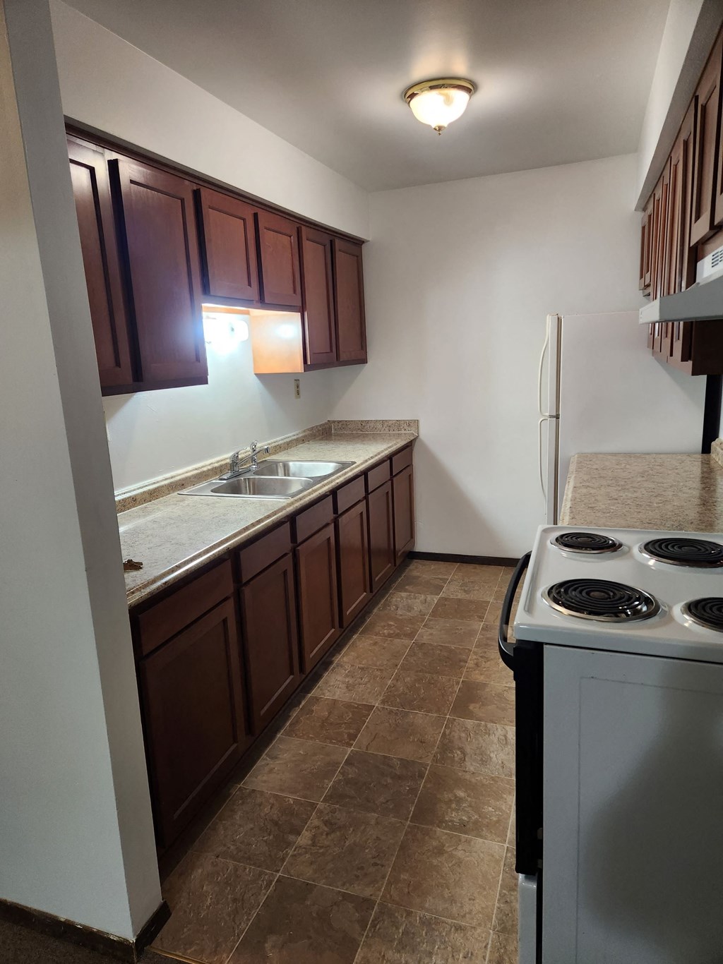 a kitchen with a stove and sink and a refrigerator
