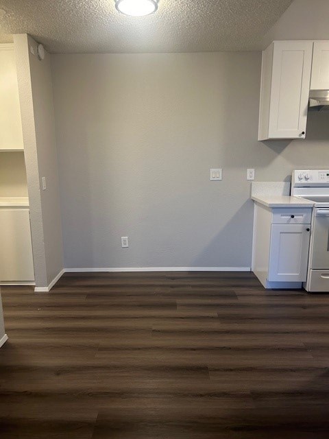 A kitchen with a white stove and wooden floors.