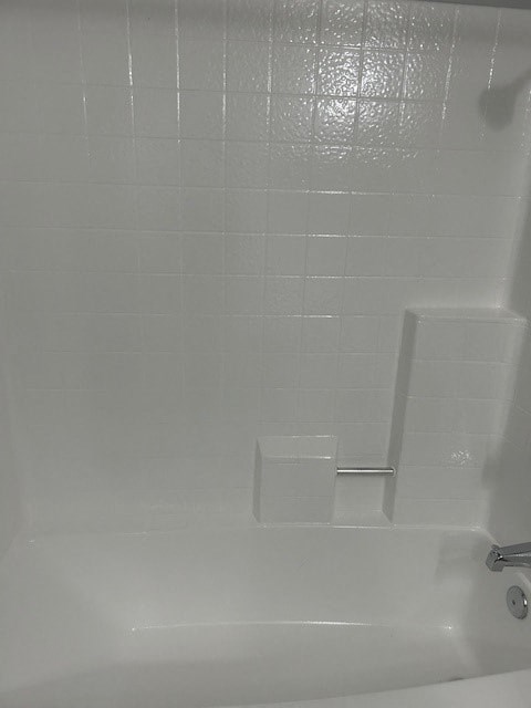 A white bathtub with a shower head and a faucet.
