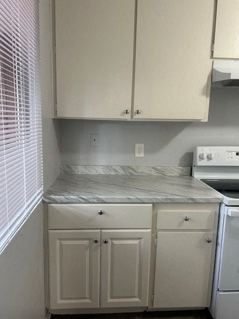 A kitchen with white cabinets and a marble countertop.