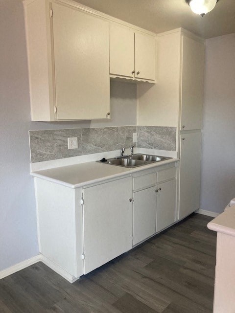 A kitchen with white cabinets and a marble backsplash.