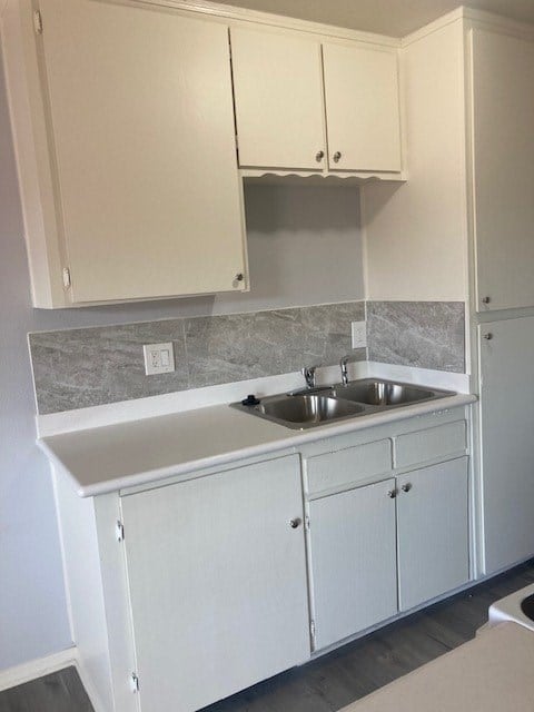 A kitchen with white cabinets and a grey counter top.