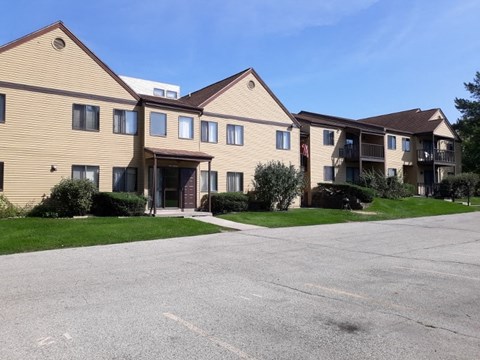A large apartment complex with a parking lot in front.