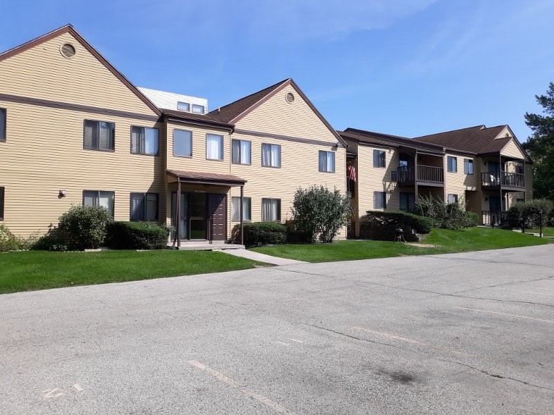 A large apartment complex with a parking lot in front.