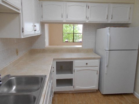 A kitchen with white cabinets and a white fridge.