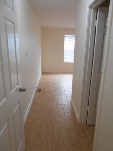 A hallway with a wooden floor and white walls.