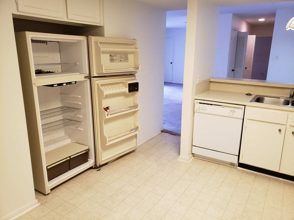 an empty kitchen with an open refrigerator and a sink
