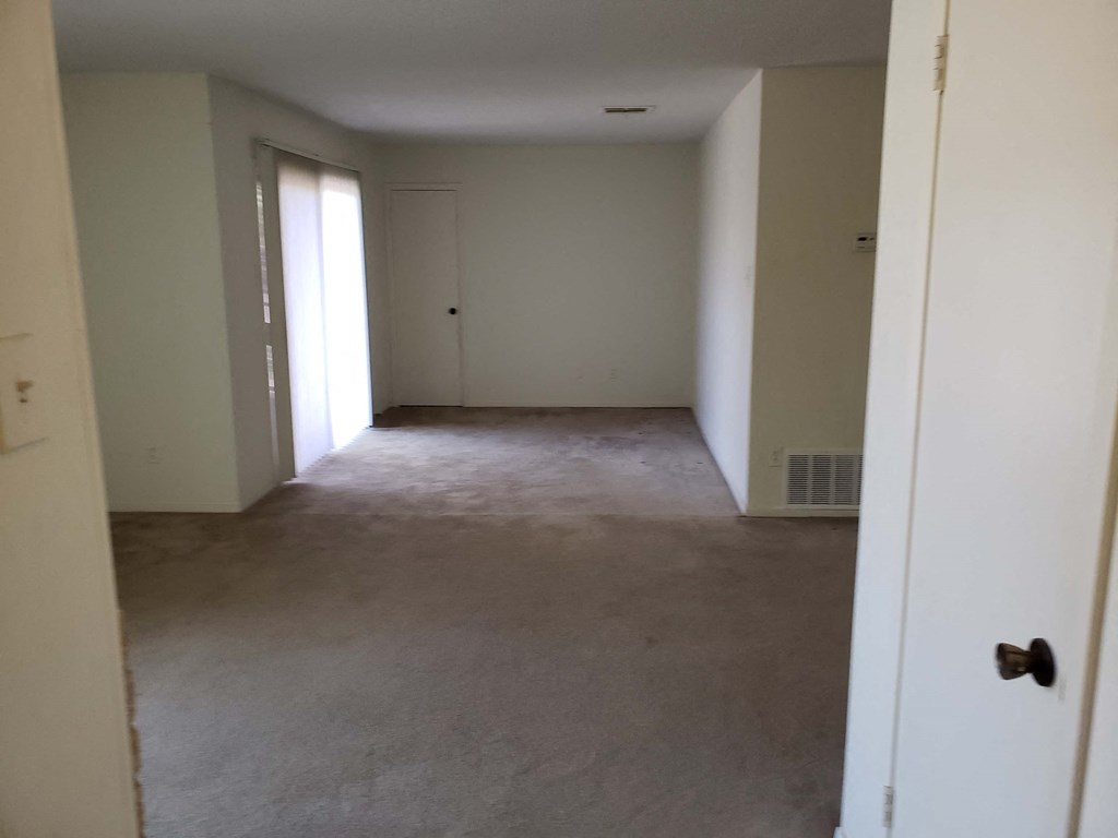 an empty room with a carpeted floor and a door to a closet