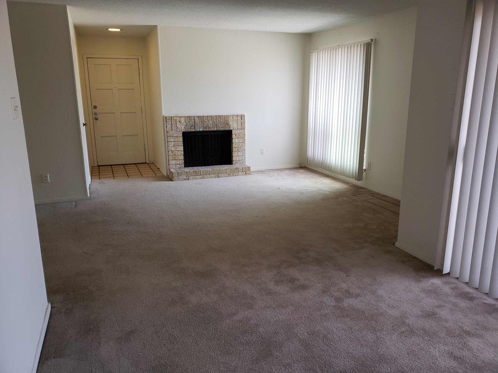 an empty living room with a fireplace and a door