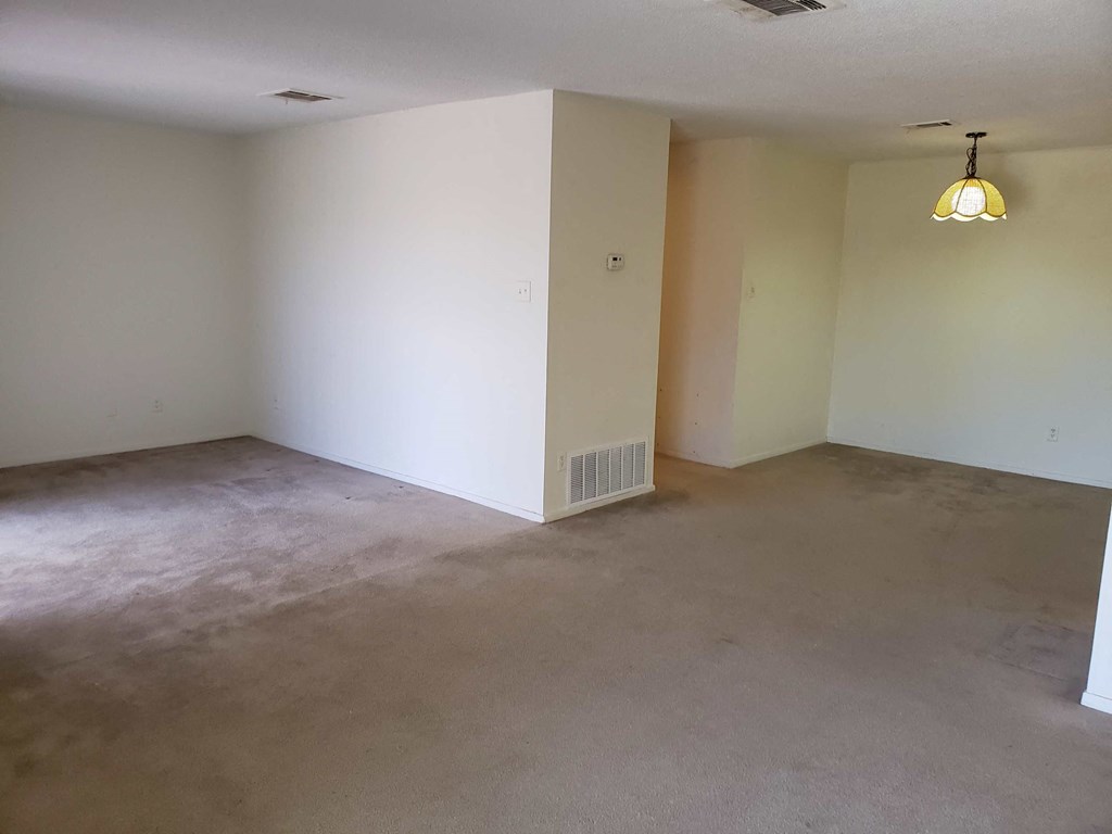 an empty living room with a white wall and a lamp