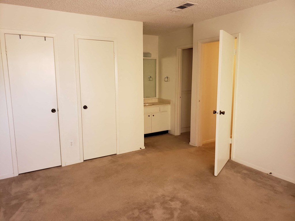 a room with a carpeted floor and white closets and doors