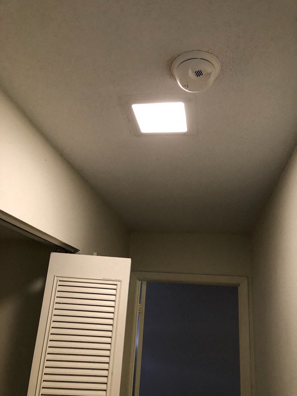 a light on the ceiling of a room with a window and a closet