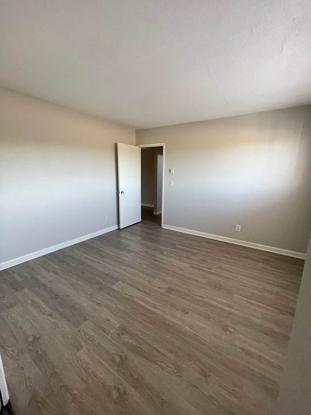 an empty living room with wood floors and white walls