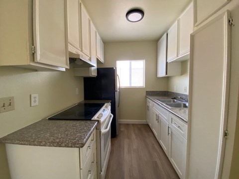 A kitchen with white cabinets and a black refrigerator.