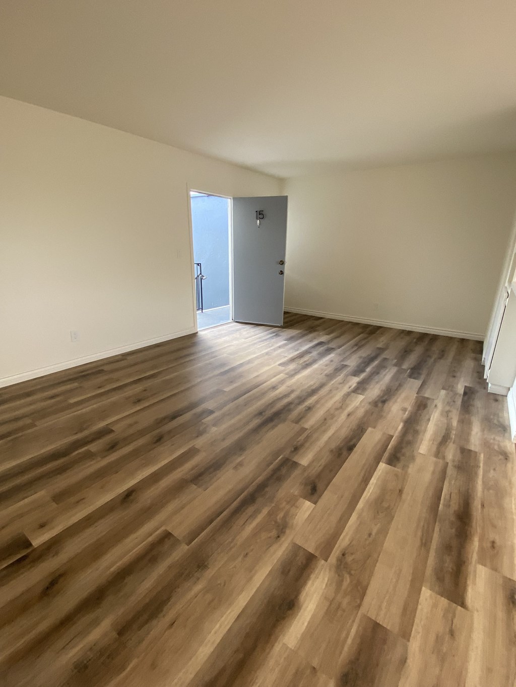 an empty living room with hardwood floors and a door to a balcony