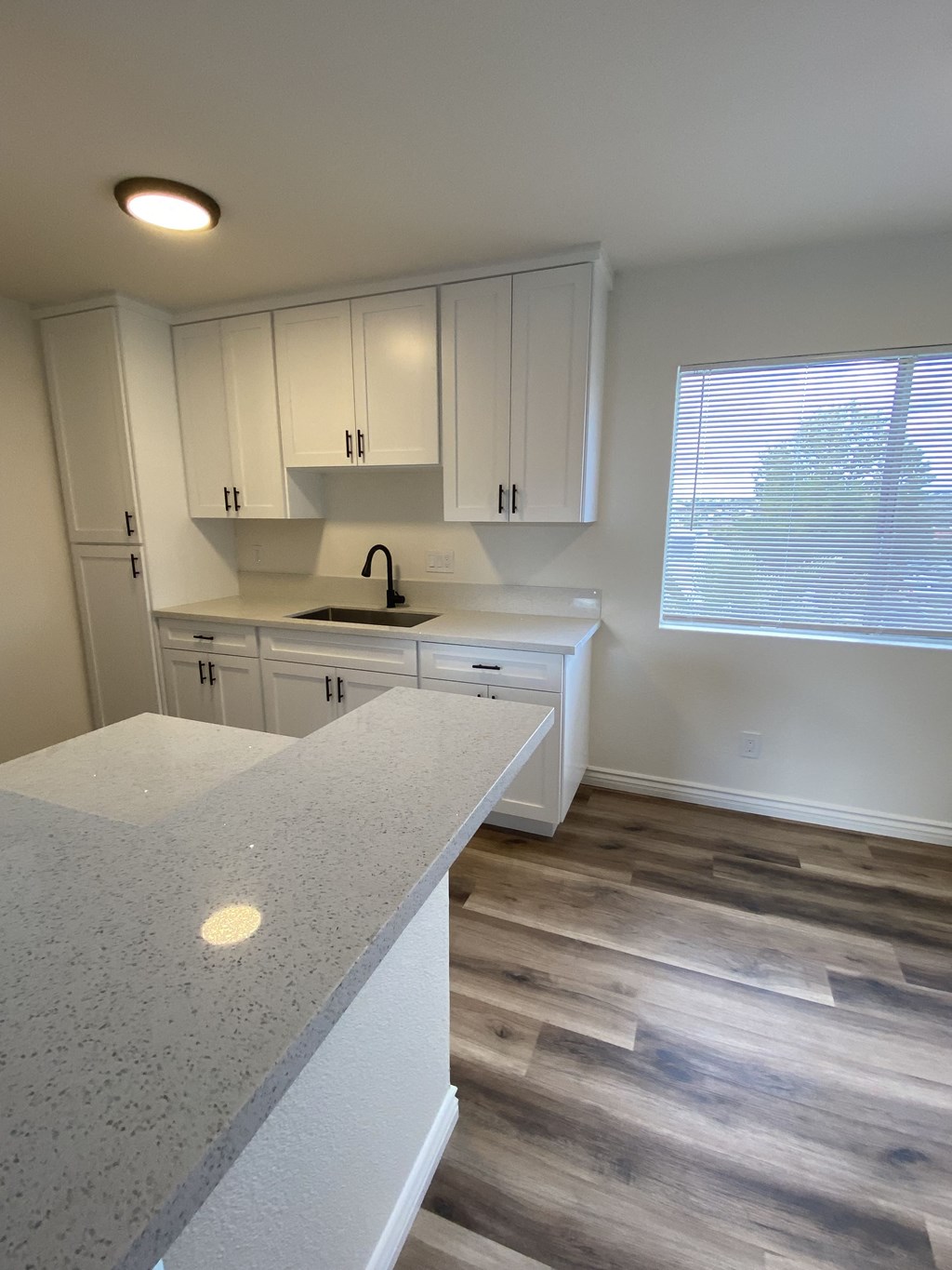 an empty kitchen with white cabinets and a window