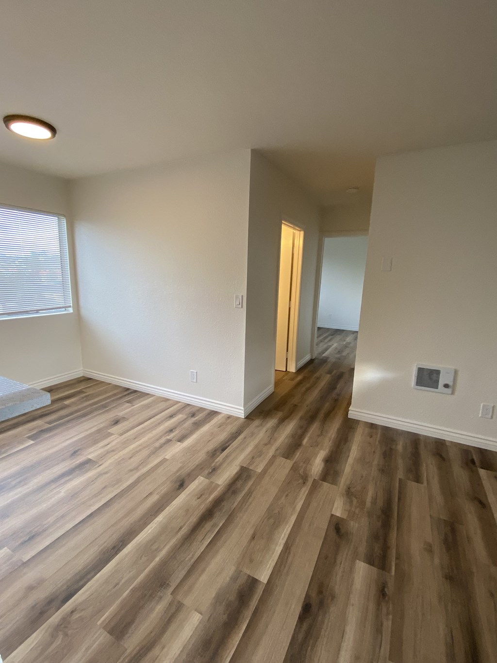 an empty living room with wood flooring and a window