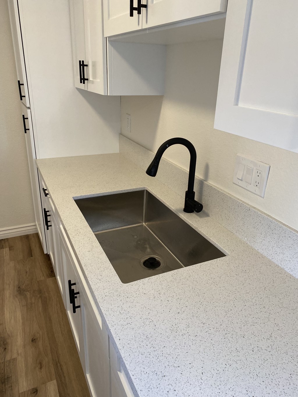 an empty kitchen with a sink and white counter tops