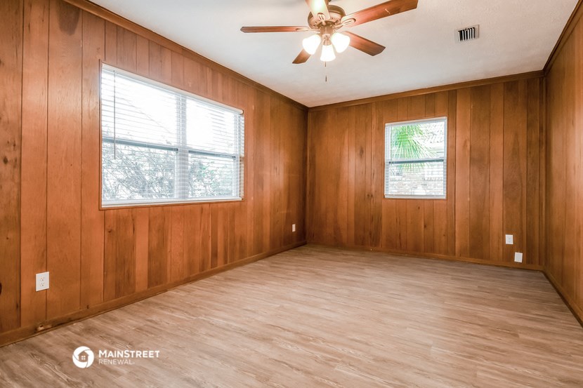 an empty room with wood floors and a ceiling fan