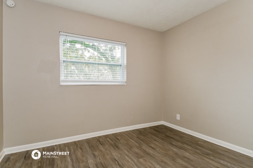 the living room of an apartment with a window and wooden floors