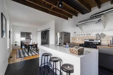 A kitchen with a white counter and black stools.