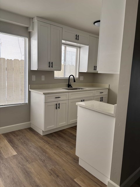 A kitchen with white cabinets and a wooden floor.