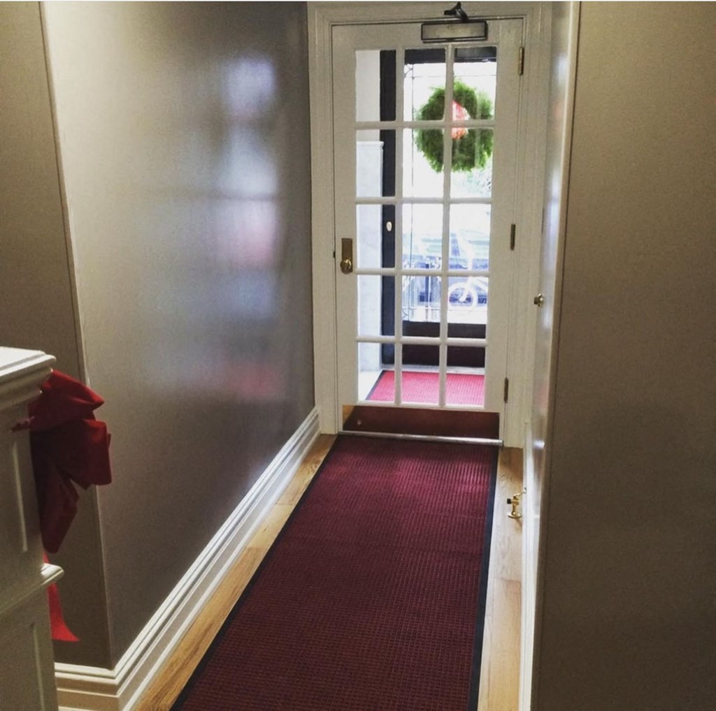 a red carpeted hallway leading to a door with a wreath on it