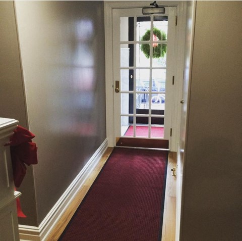 a red carpeted hallway leading to a door with a wreath on it