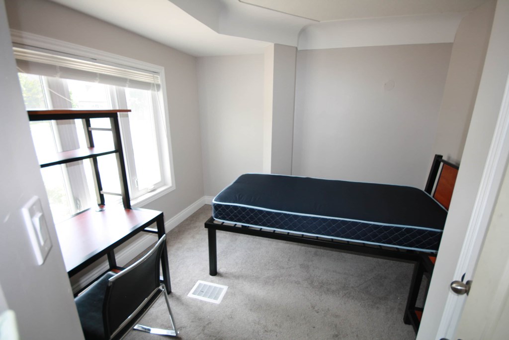 A small bedroom with a bed, desk, and chair.