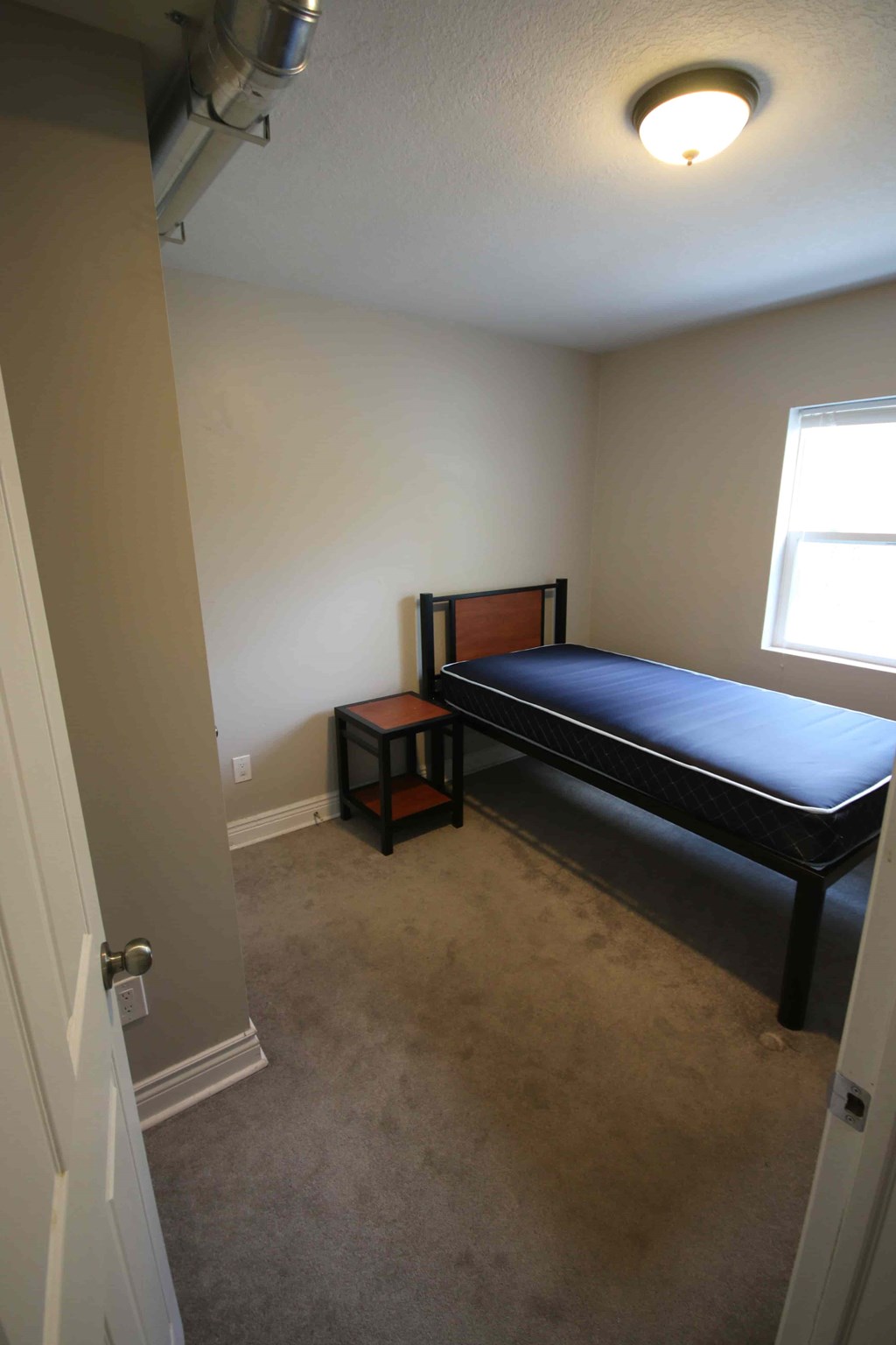 A bedroom with a bed and a small table.