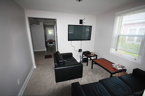 A living room with a black couch and a television.