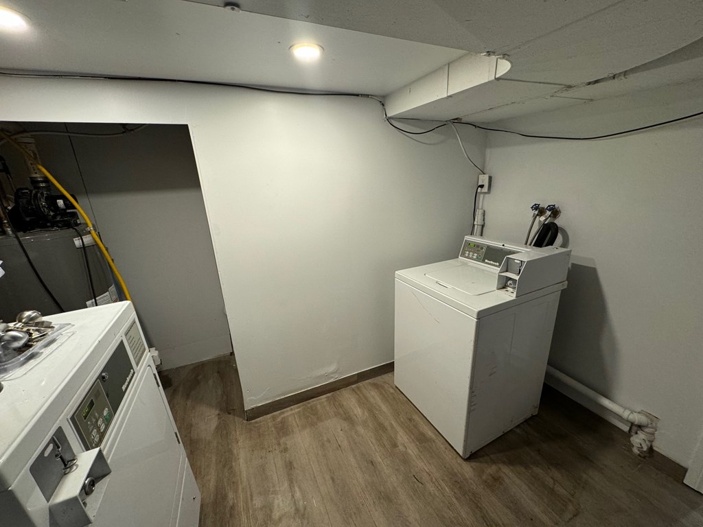 A white appliance sits in a room with a wooden floor and white walls.