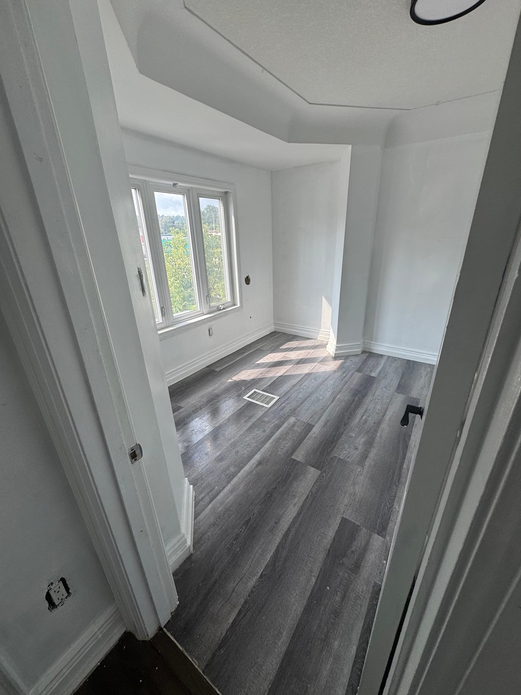 A room with a window and wooden flooring.