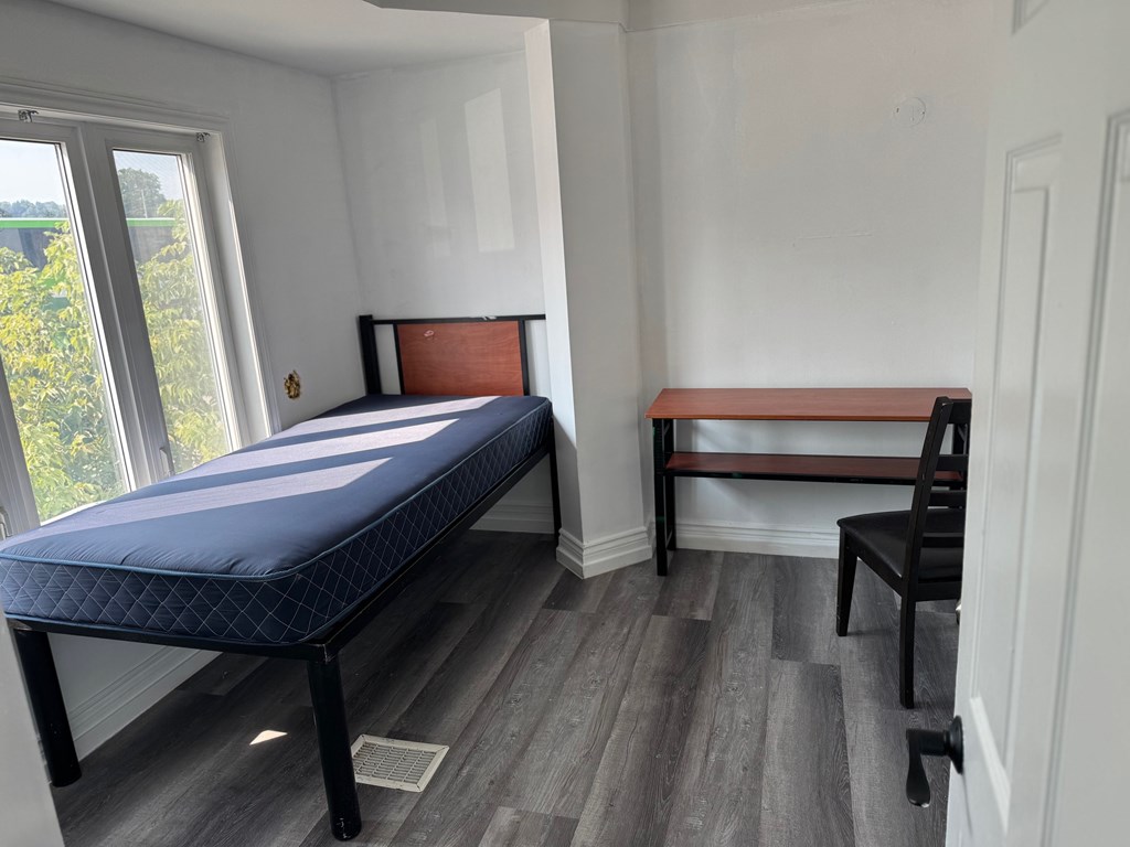 A bedroom with a bed, chair, and window.