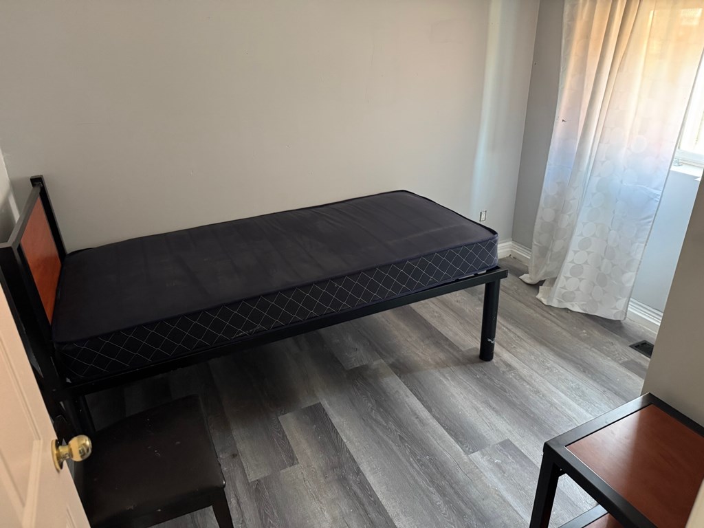 A black metal bed frame with a mattress and a small table.