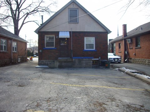 A small brick building with a porch and a car parked in front.