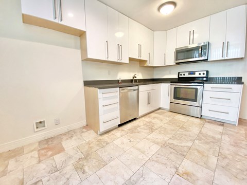 an empty kitchen with white cabinets and stainless steel appliances