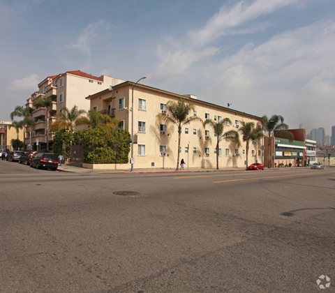 an apartment building on the corner of a street with palm trees