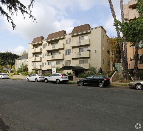 a street with cars parked in front of an apartment building