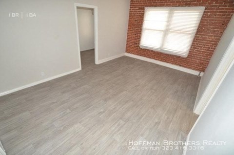 an empty room with a brick wall and wood floors